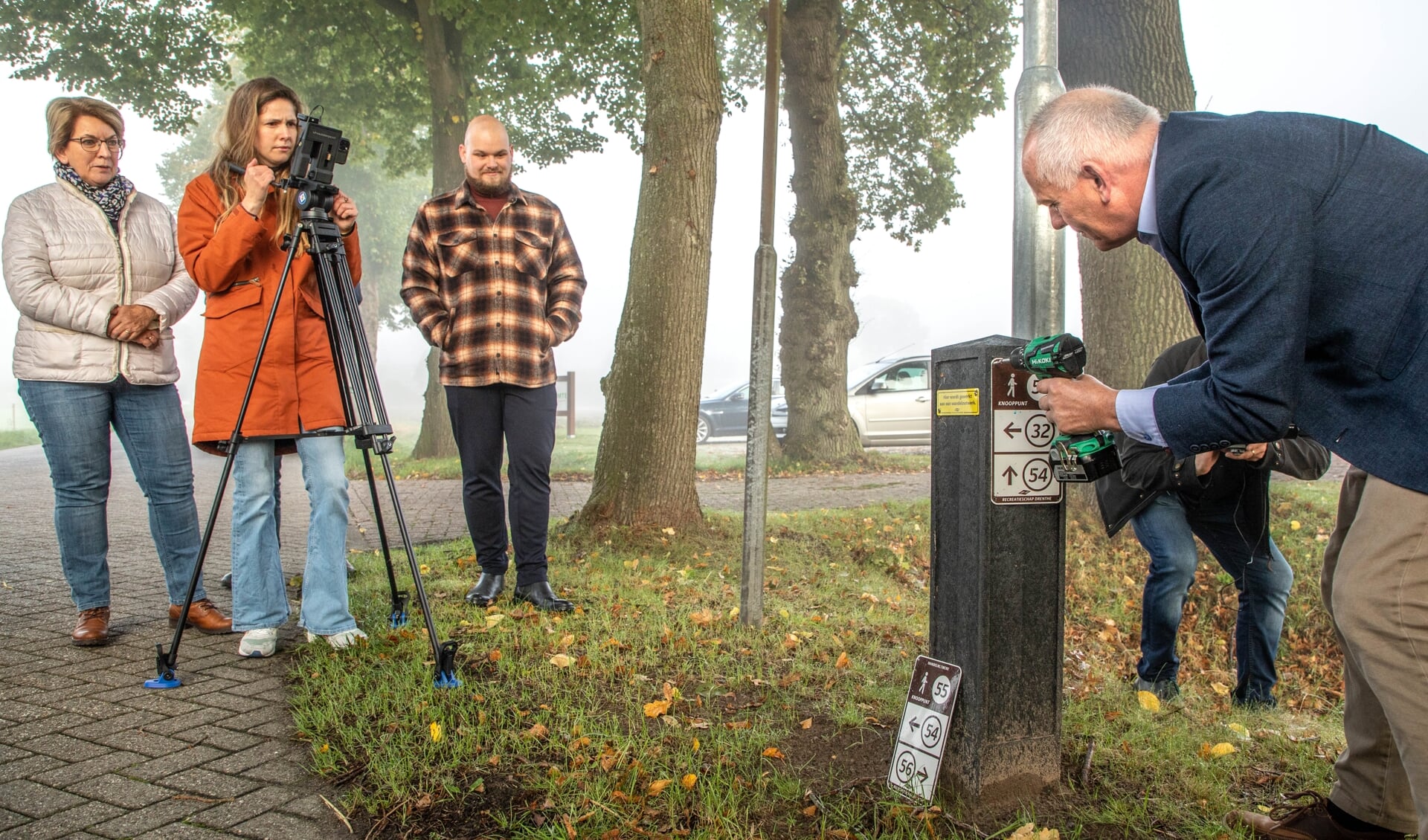 Gedeputeerde Henk Brink schroeft het laatste knooppuntbordje vast onder toeziend oog van wethouder Nynke Houwing (links). (foto: Auniek Klijnstra)