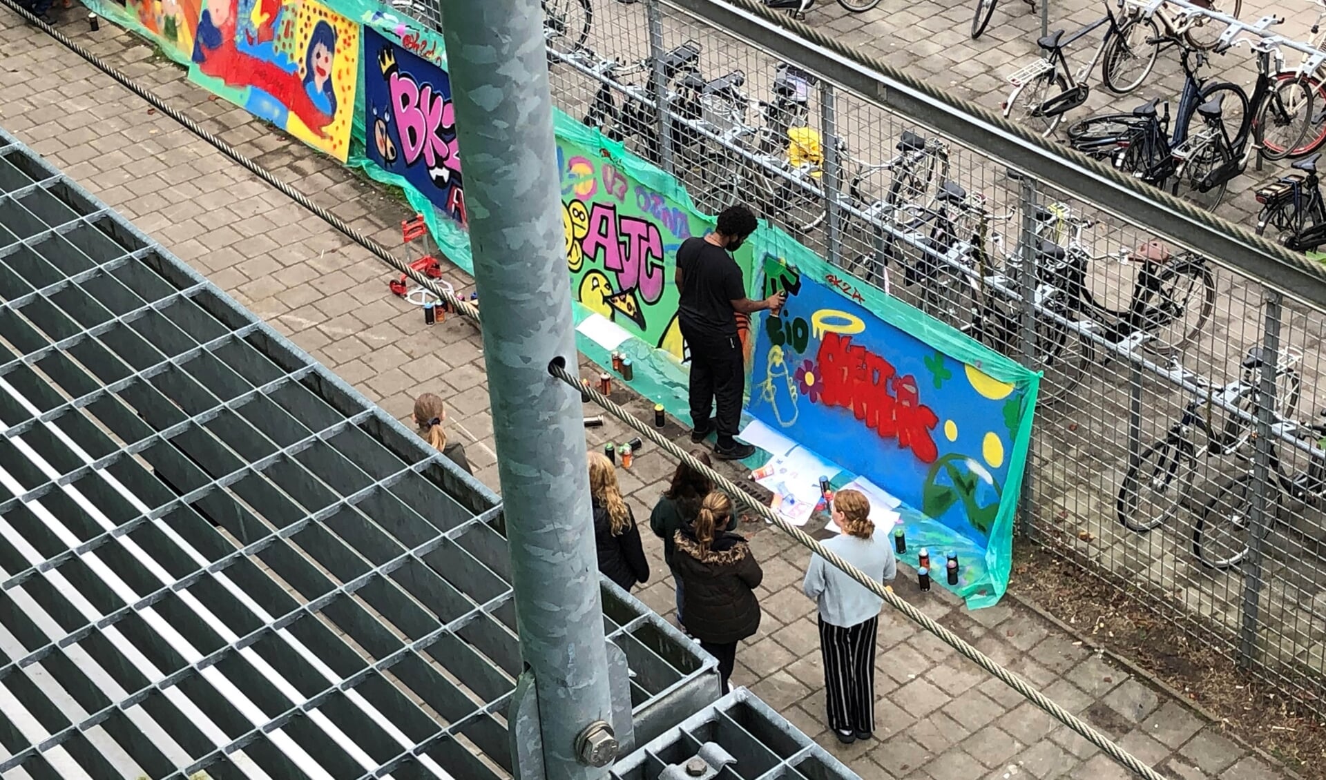 Professionele graffitikunstenaars en leerlingen uit klas 2 bezig op het schoolplein