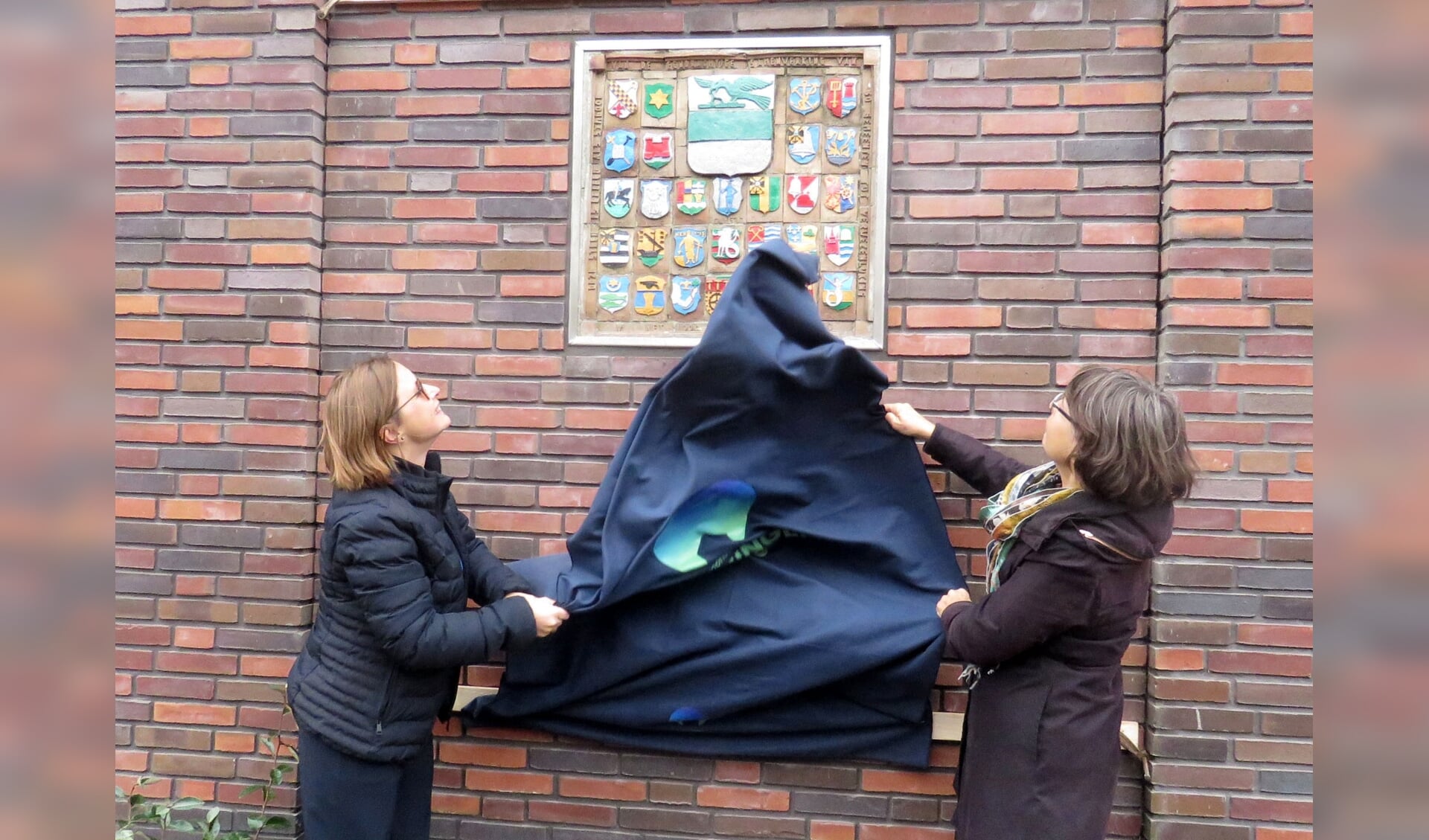 Laura Broekhuizen en wethouder José van Schie onthullen de historische keramieken gevelsteen.