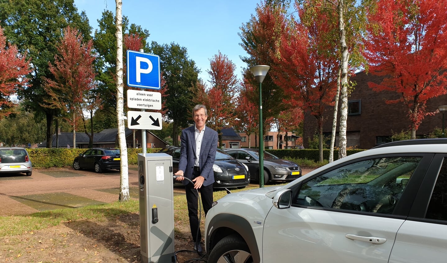 Wethouder Co Lambert plugt de eerste elektrische auto in op de parkeerplaats bij het gemeentehuis in Gieten. (foto: gemeente Aa en Hunze)