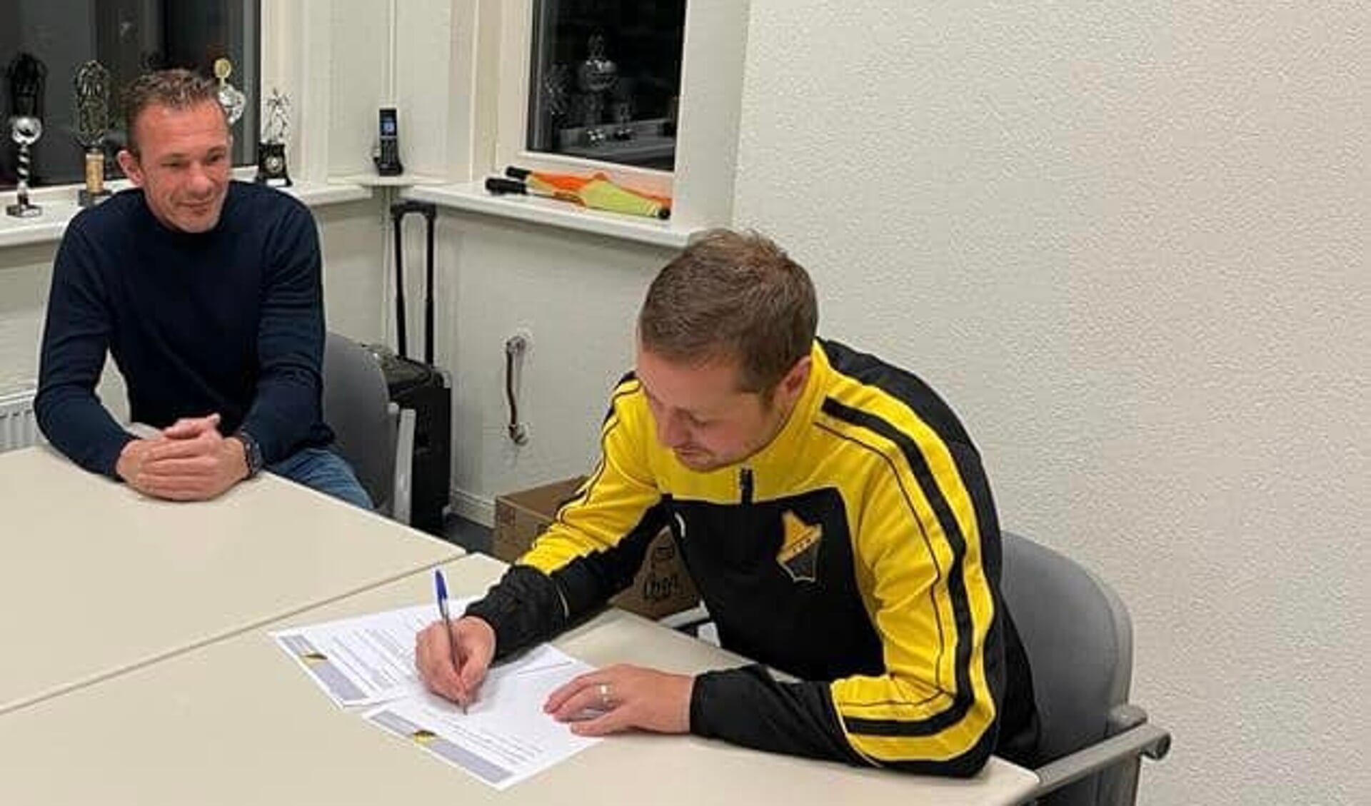 Nico de Vries (rechts) tekent het contract. Voorzitter Jelte van der Kooi kijkt tevreden toe.