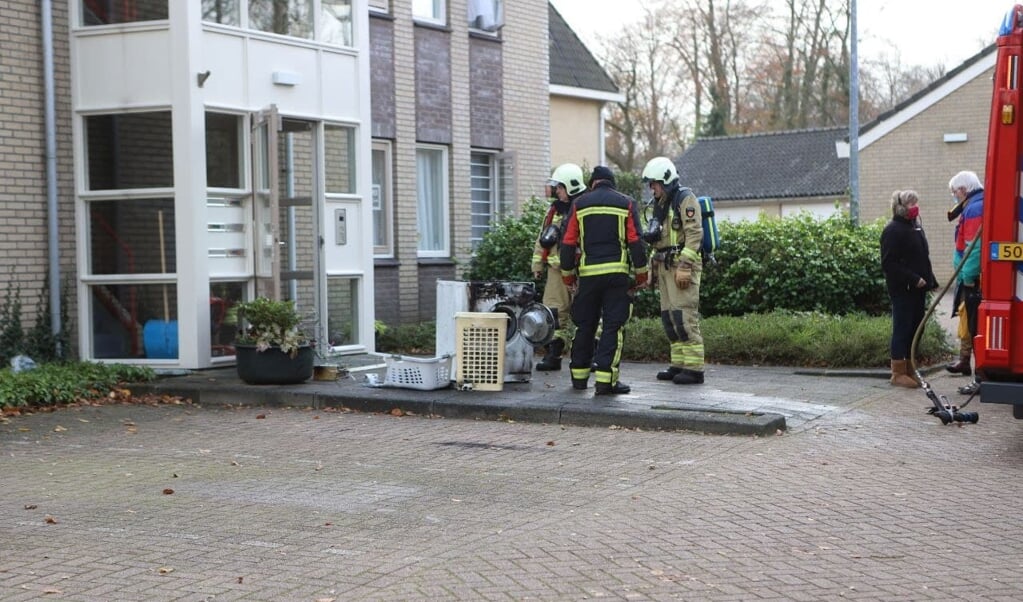 De in brand gevlogen wasmachine is door de brandweer uit het appartement gehaald. (foto: Persbureau Drenthe)