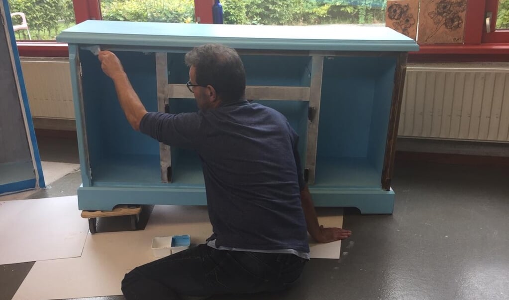 Een van de cliënten van Cosis De Regenboog is druk bezig met het schilderen van een kast. (foto: Roelinka Bos)