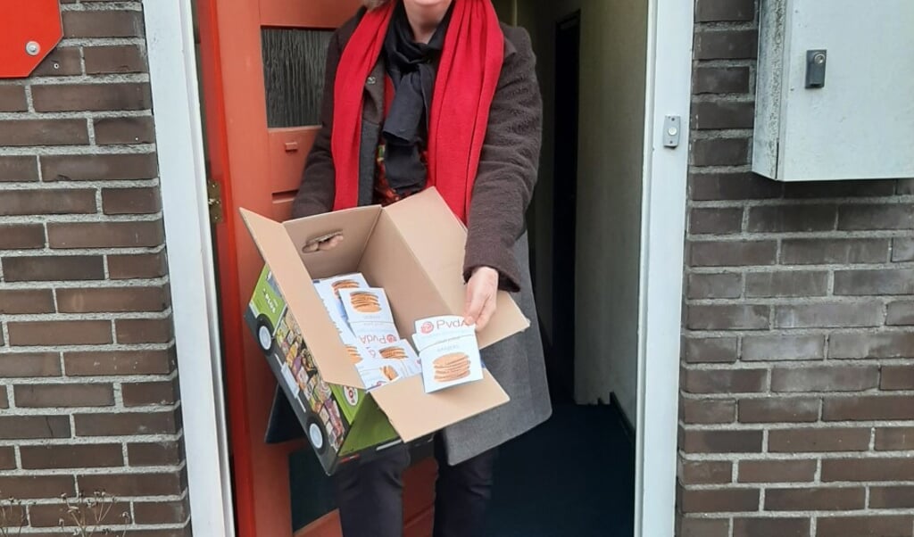 PvdA-fractievoorzitter Thea van der Veen neemt dozen met kanjerkoeken in ontvangst om ze later uit te delen.