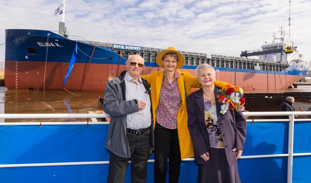 Een stralende Elisa Kruit met bloemen en champagne na de doop van het schip met haar ouders, Berend en Inge Kruit uit Hoogezand.