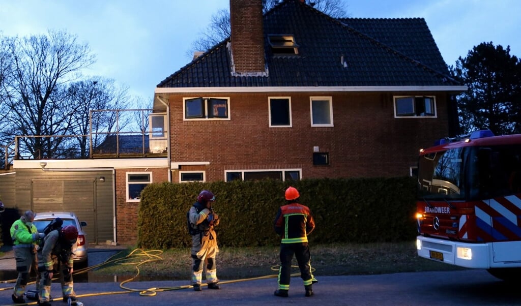 De brandweer bestrijdt de schoorsteenbrand.