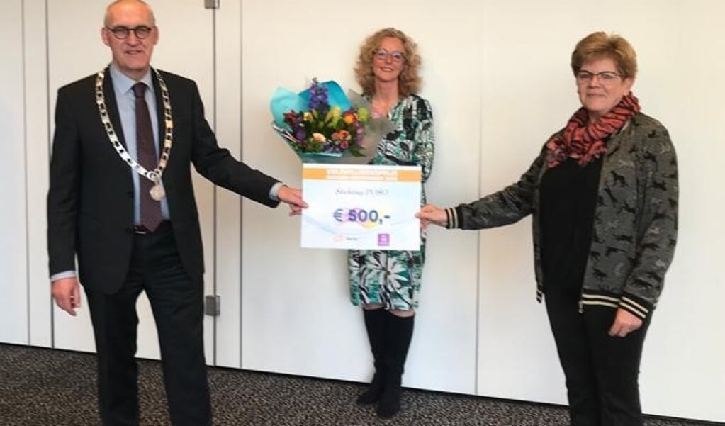 Burgemeester Hoogendoorn en Adriana Jaarsma (midden) reiken de prijs uit aan één van de winnaars, Ina Slagter van Stichting POSO.
