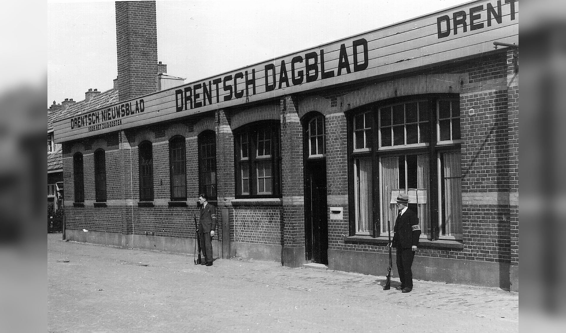 Twee leden van de Binnenlandse Strijdkrachten bewaken na de bevrijding het gebouw van drukkerij de Agrarische Pers in Meppel. Hier werd tijdens de oorlog het door de bezetter opgerichte en dus 'foute' Drentsch Dagblad gedrukt.