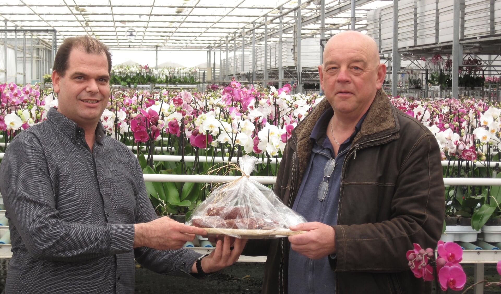 Directeur Piet Aardse van Aardse Orchids (links) ontvangt namens het bestuur van ZNC een worstplankje.