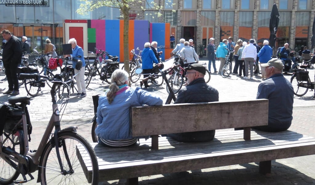 Senioren wachten op het plein bij het gemeentehuis op de start van de fietstocht.