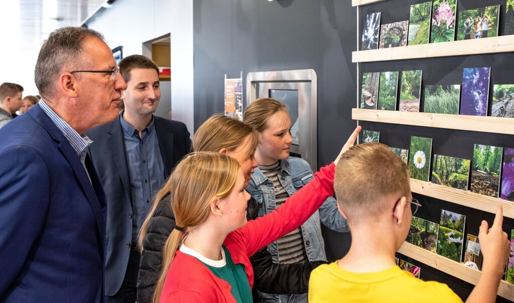 Fotograaf André Dümmer en wethouder Wietze Potze bekijken samen met de kinderen de foto's. (foto: Auniek Klijnstra)