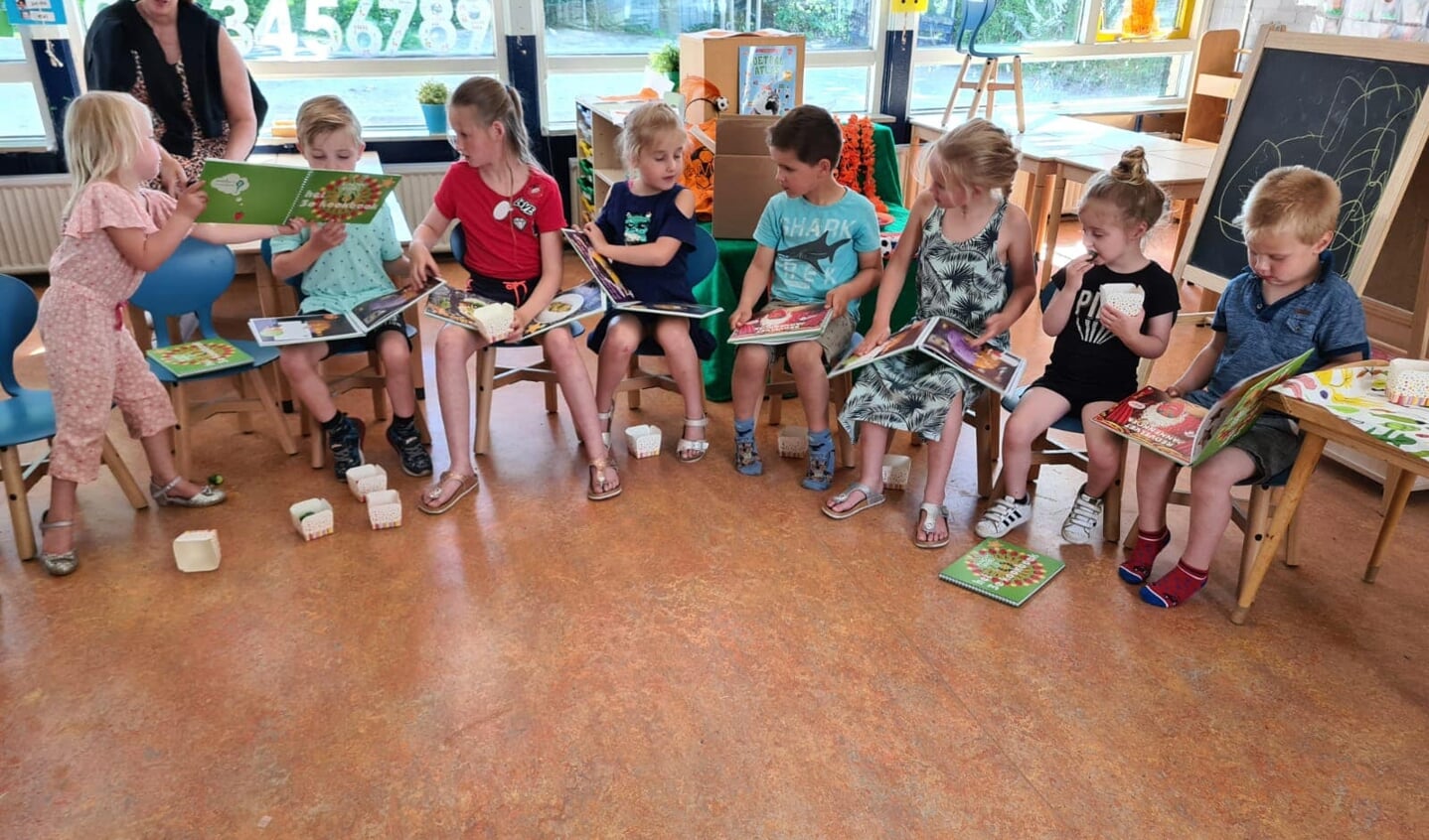 Kinderen van IKC de Bosvlinder lezen in het kookboek met daarin ook hun recept (foto Gemeente Midden-Drenthe).
