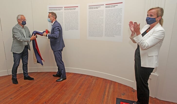CdK René Paas haalt een Nederlandse vlag weg voor een deel van de tentoonstelling. Daarvoor eeed de klappende Letse ambassadeur Aiga Liepina dat al met een Letse vlag. Foto: Bert Woltjes.  