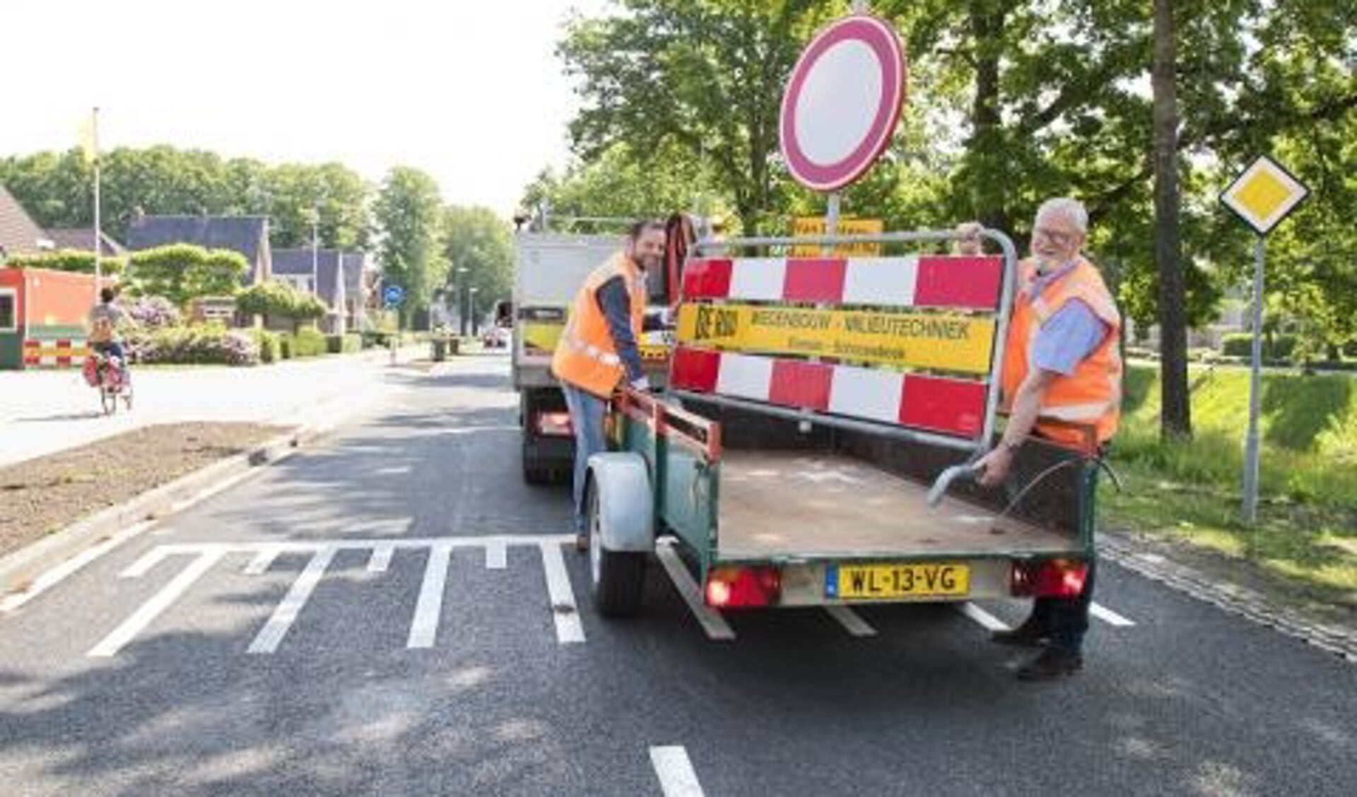 Verkeerswethouder René van der Weide (links) zet samen met Henk de Roo, directeur van De Roo Wegenbouw-Milieutechniek, de afsluitingsborden opzij. Verkeer is weer welkom op het Van Echtenskanaal. Foto: Bianca Verhoef.