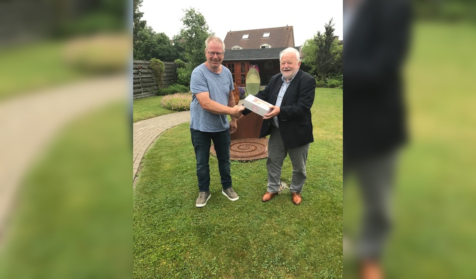 Voorzitter Bert Kolk van Stichting Gasthuis Hoogezand-Sappemeer biedt vrijwilliger Harry Jager gebak aan.