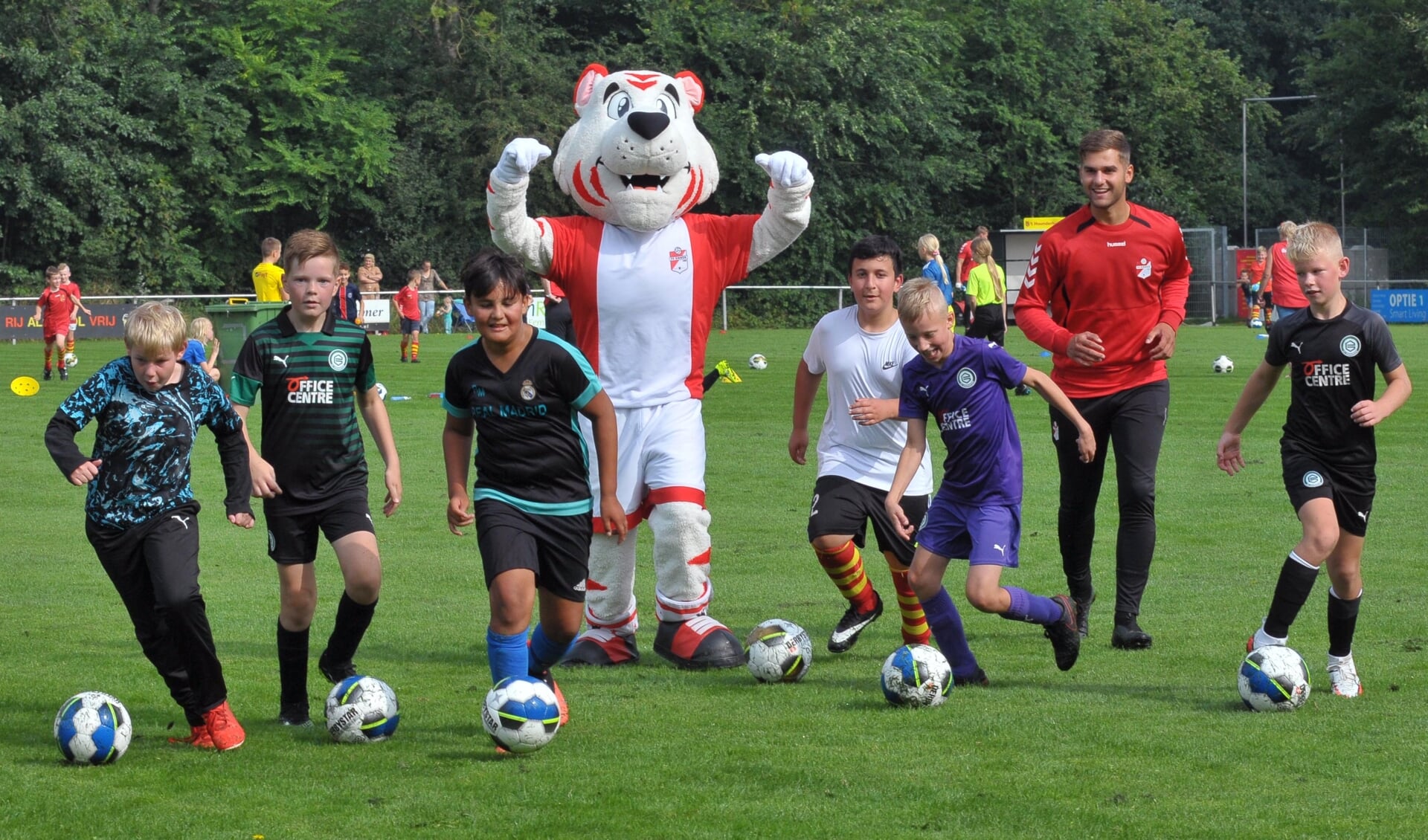 Jonge voetballertjes oefenen het dribbelen onder het toeziend van de FC Emmen-mascotte.