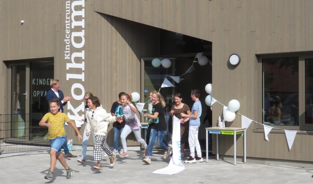 De kinderen rennen onder applaus van wethouder Drenth (links) het gebouw uit, waarmee de officiële opening van Kindcentrum Kolham een feit is.