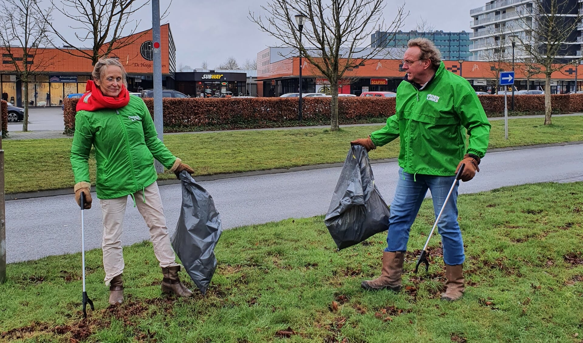 Silvia Poel en Jan Poel van GroenLinks Midden-Groningen ruimen zwerfafval op bij winkelcentrum De Hooge Meeren.