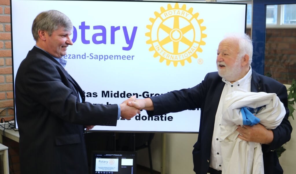 Humanitas-voorzitter Bert Kolk neemt het tv-scherm in ontvangst ven Rotary-secretaris Ruud Bank.