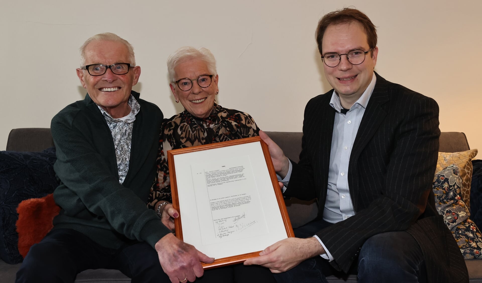 Wethouder Egbert Hofstra overhandigt Gezienus en Lenie Hulshof een ingelijste kopie van hun trouwakte. (foto: Herman van Oost) 