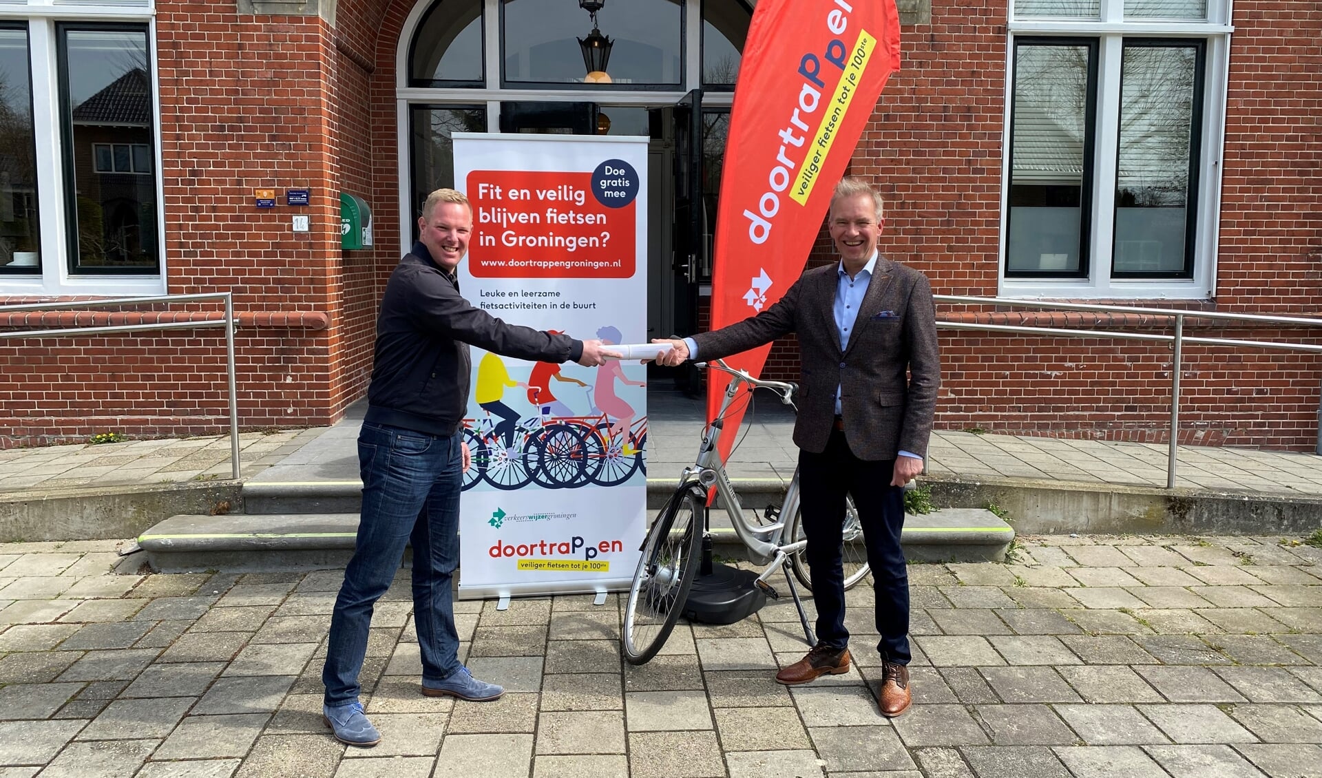 Wethouder Meindert Joostens (rechts) neemt campagnematerialen in ontvangst als startsein voor 'Doortrappen Groningen' in de gemeente Eemsdelta.