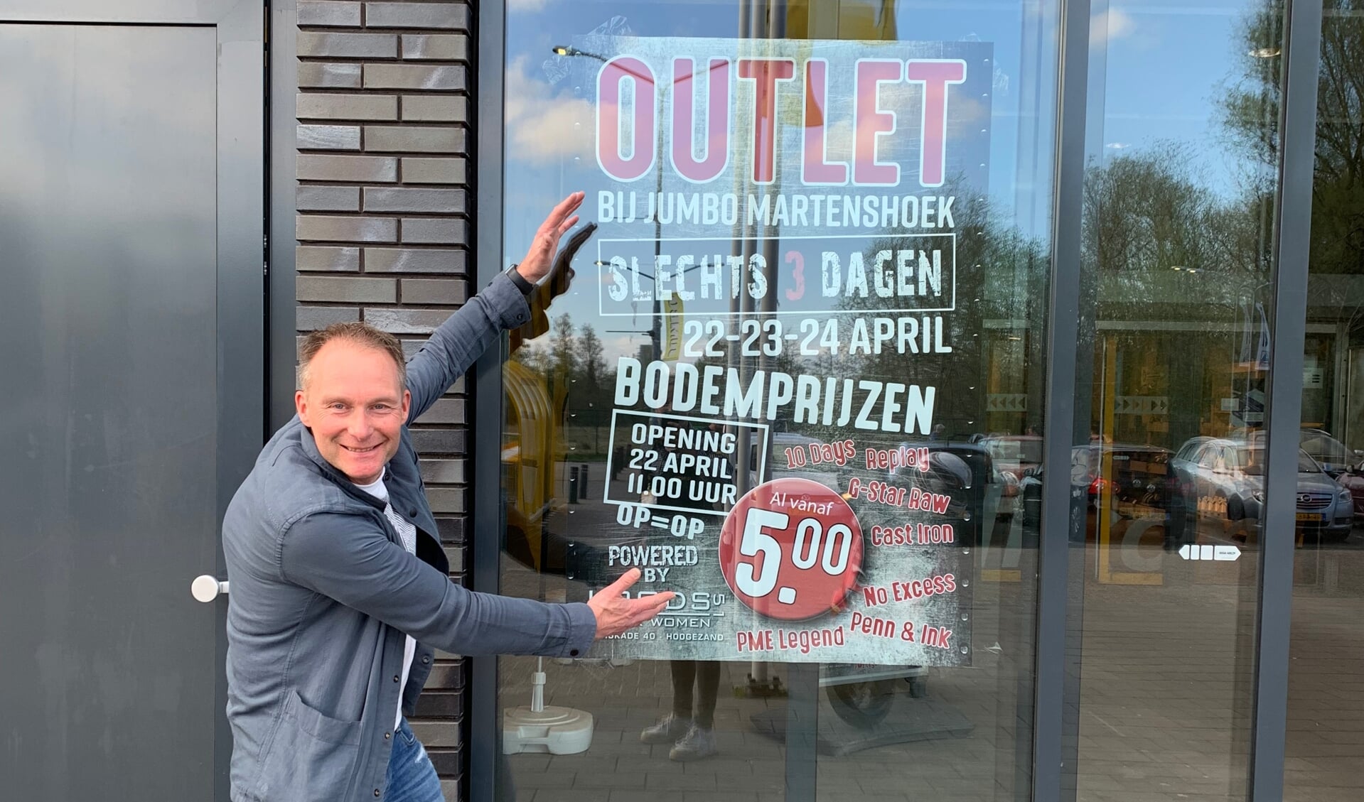 Remie Groeneveld bevestigt een poster van de outlet bij Jumbo in Martenshoek.