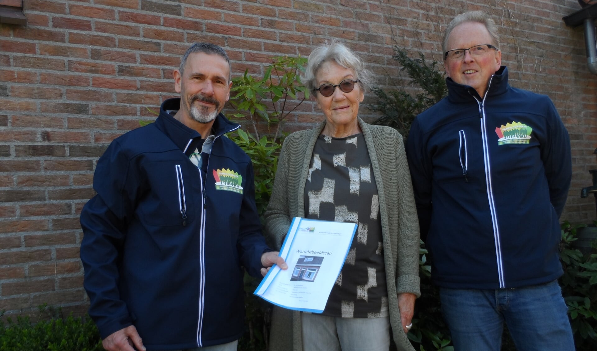 De warmtescanners Gerrit de Jong en Ugo Leever overhandigen het rapport aan Anneke Kinds-Roelfsema.