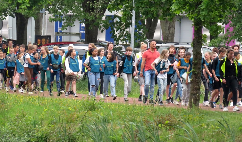 Deelnemers aan de Avondvierdaagse trekken door de straten van Hoogezand-Sappemeer.