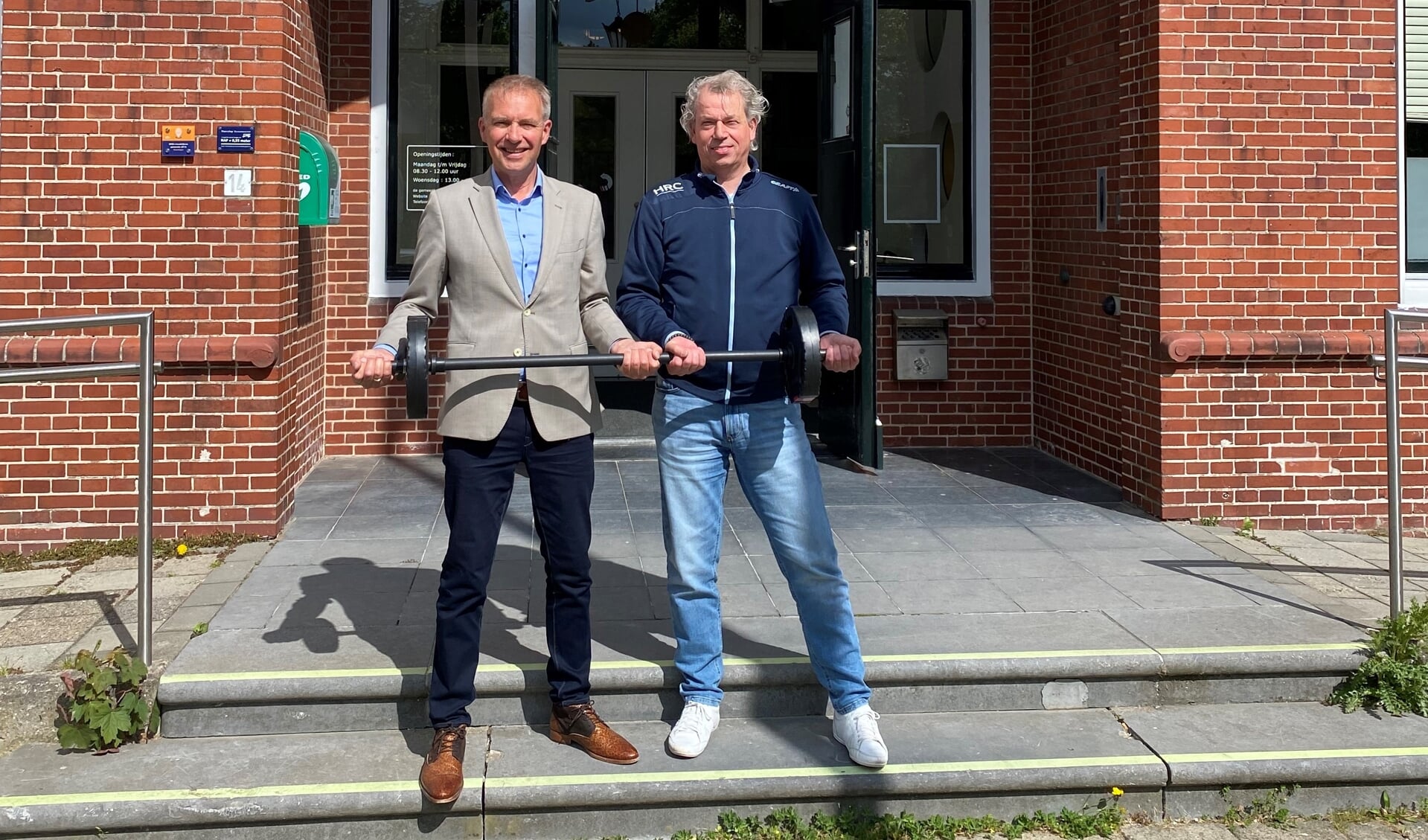Wethouder Meindert Joostens en Jeroen Laarhuis (HRC Powerful Ageing) tillen gezamenlijk een halter om de samenwerking te bekrachtigen.