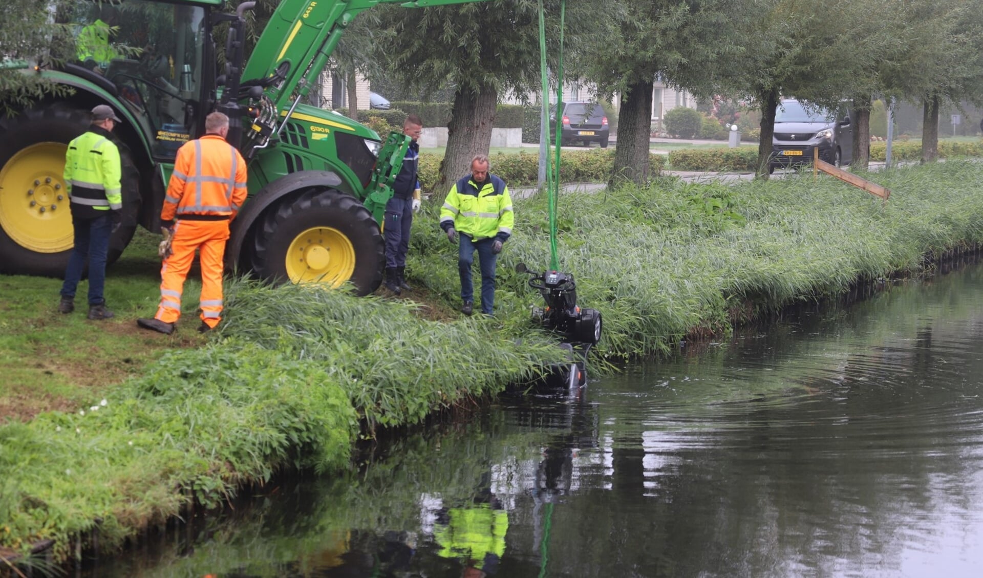 De scootmobiel werd met een tractor uit het water gehaald. (foto: Persbureau Groningen)