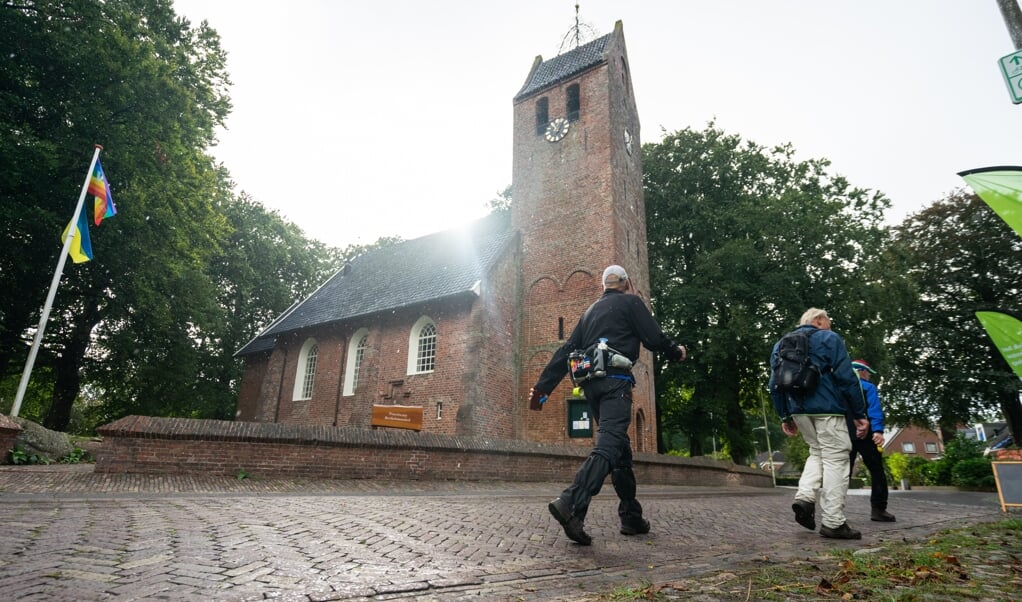 Deelnemers aan de Hunzeloop Wandeltocht passeren de Bartholomeuskerk in Noordlaren. (foto Liam Kuiper/LK Media)
