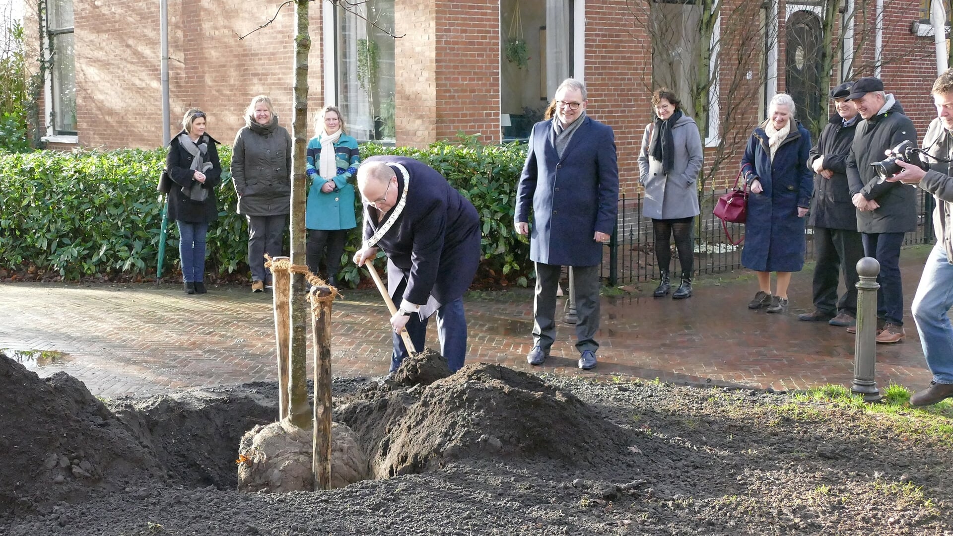 Ben Visser plant 'zijn' boom. Onder de supporters ook raadsnestor Bert Raangs (foto Gemeente Eemsdelta).