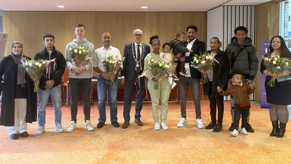 De nieuwe inwoners met de bloemen en in hun midden burgemeester Hoogendoorn. 