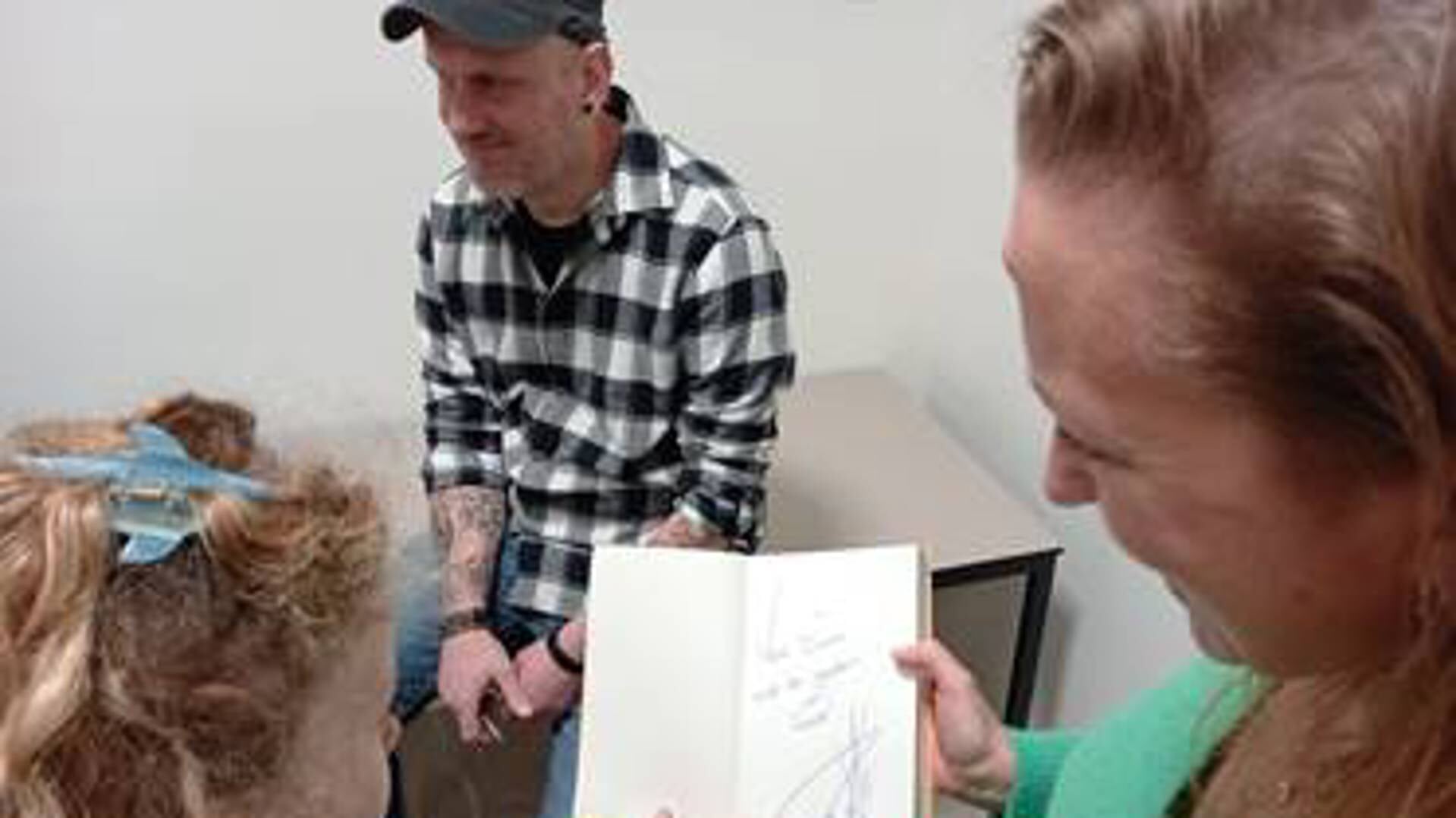 Leerlingen uit groep 5/6 kijken samen met de leerkracht naar de handtekening van Pieter Koolwijk in de kaft van het boek.