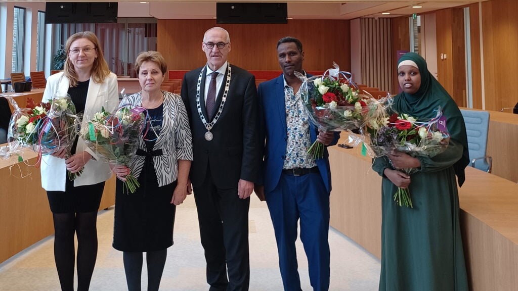 Vier van de zeven nieuwe inwoners met bloemen en in hun midden de burgemeester. (foto: gemeente Midden-Groningen)