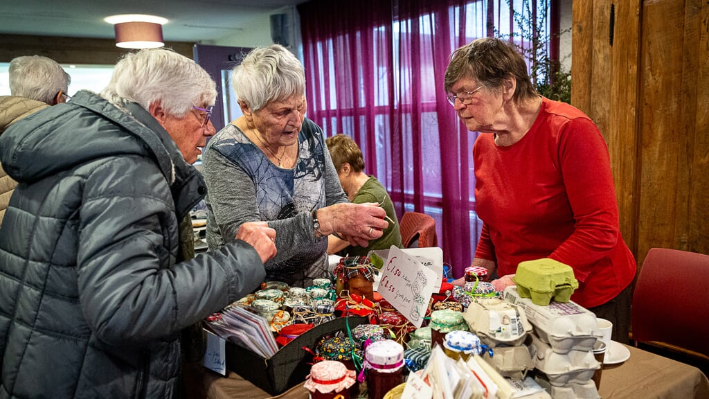 Bezoekers van de Wintermarkt in De Wenning kijken of er iets van hun gading bij is. 