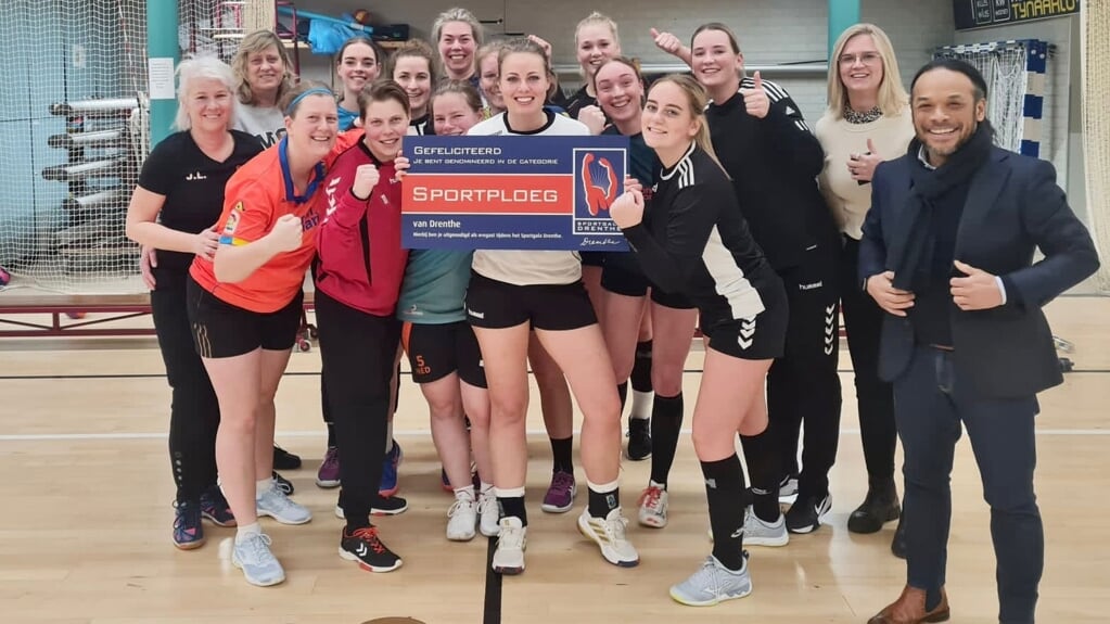 De handbaldames van VAKO 1 samen met wethouder Miguel Ririhena en de uitnodiging voor het sportgala.