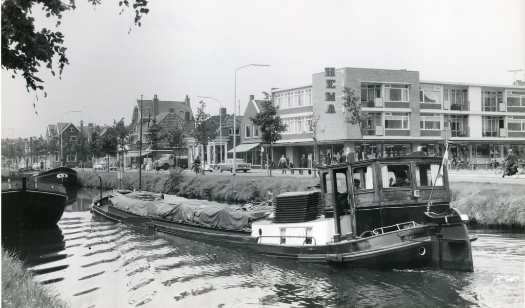Het Stadskanaal langs de Hoofdstraat met een vol vrachtschip zoals in de jaren '60 nog veelvuldig was te zien. (foto: collectie Streekhistorisch Centrum/Jospe 32102)