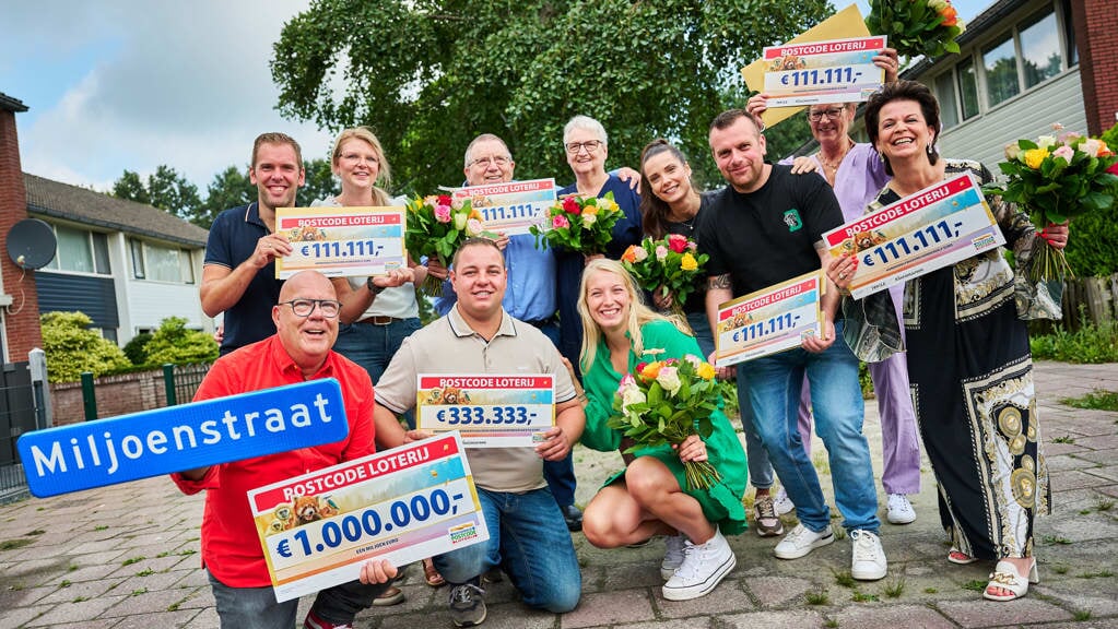 De dolgelukkige inwoners van Klazienaveen met de cheques en loterij-ambassadeur Gaston (foto Postcode Loterij).