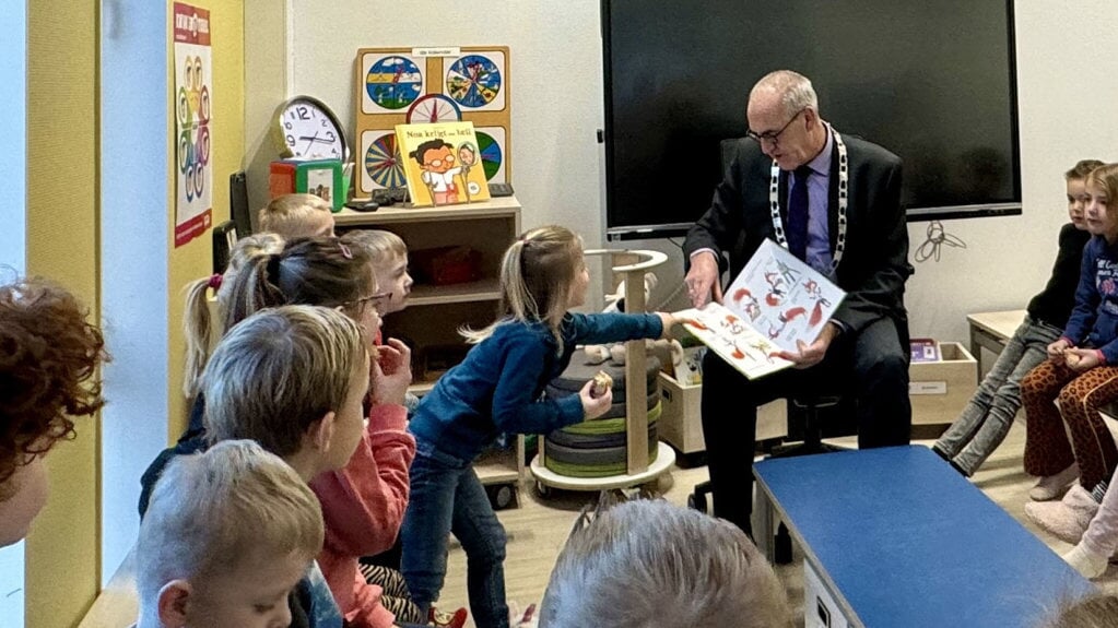 De kinderen doen actief mee bij het voorlezen door de burgemeester in Schildwolde.