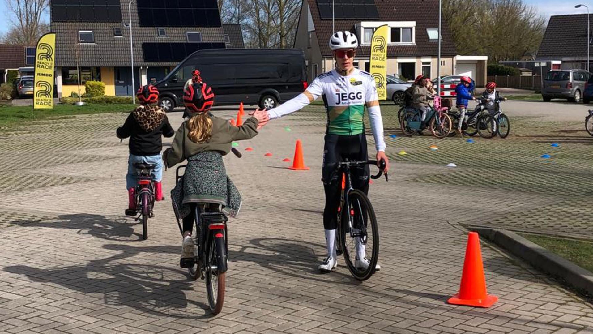 Merijn de Haan laat kinderen in Spijk kennismaken met de wielersport.