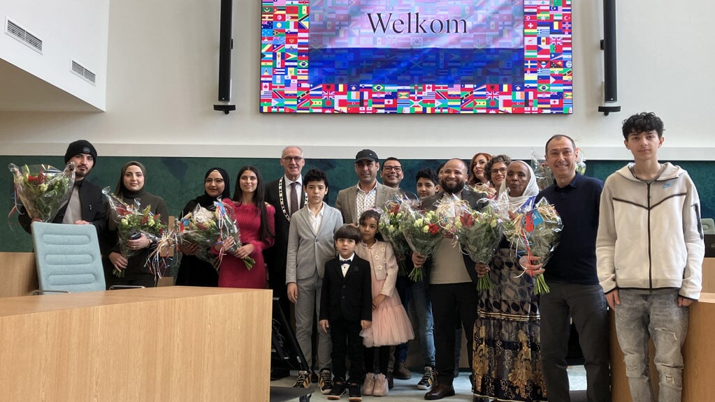 De zeventien nieuwe Nederlanders met in hun midden burgemeester Hoogendoorn. (foto: gemeente Midden-Groningen)