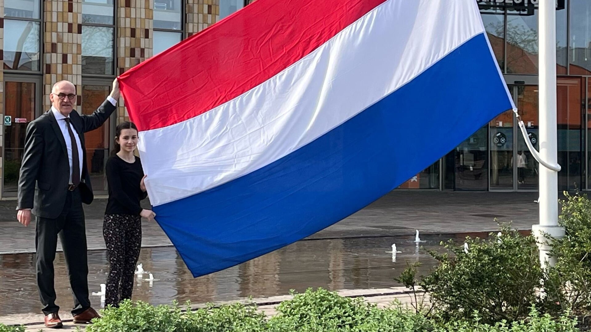 Burgemeester Hoogendoorn en kinderburgemeester Belinay Babuscu staan op het punt samen de vlag te hijsen. 