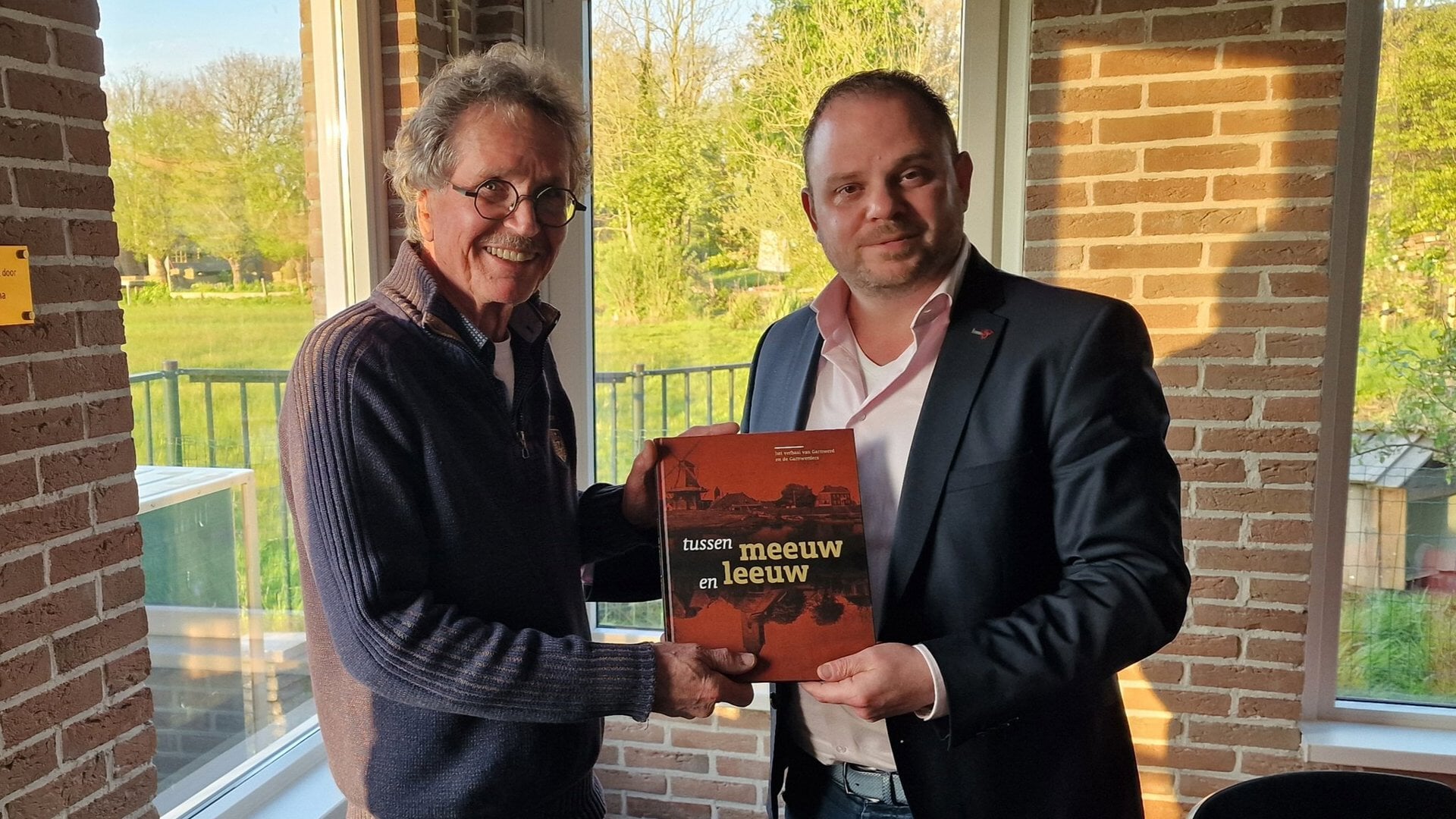 Wethouder Richard Lamberst ontving uit handen van Fokko Leutscher het boek 'Tussen Meeuw en Leeuw'  