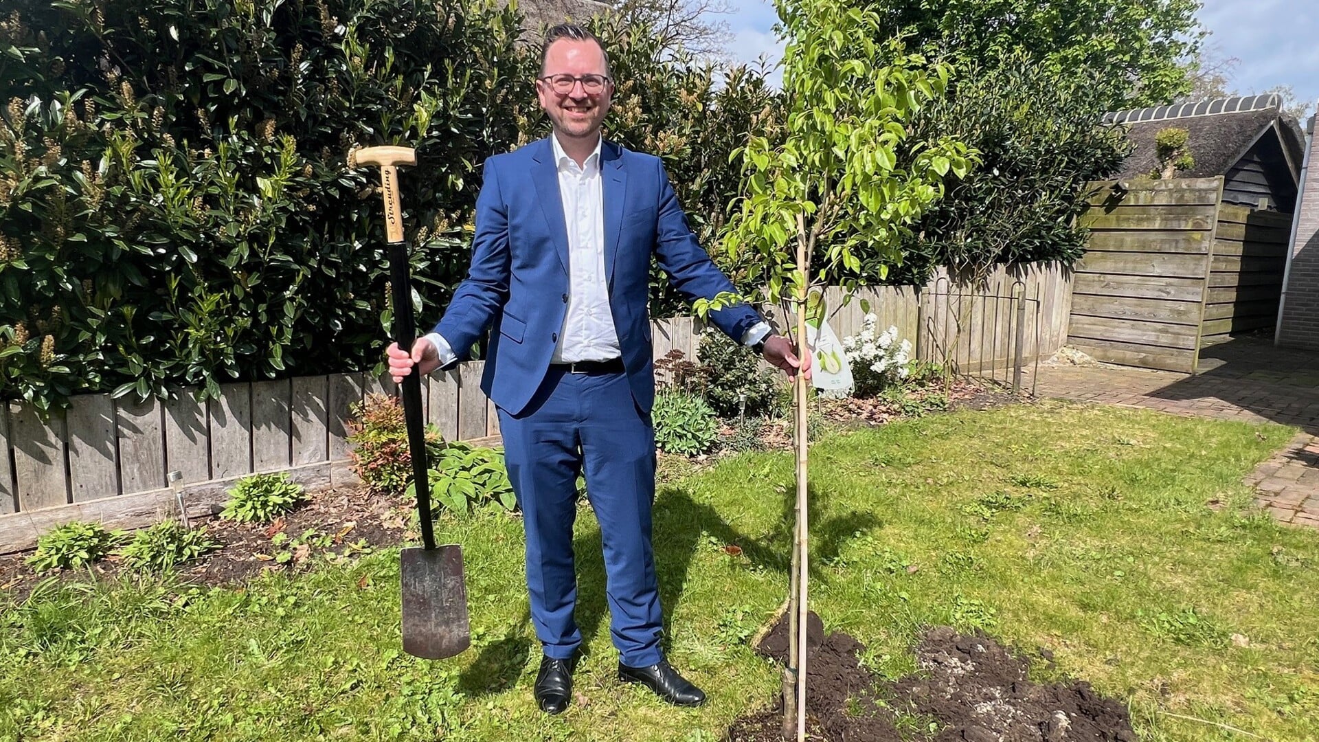 Wethouder Jeroen Hartsuiker plant een perenboom in de tuin van een inwoner van de gemeente. (foto: gemeente Borger-Odoorn)