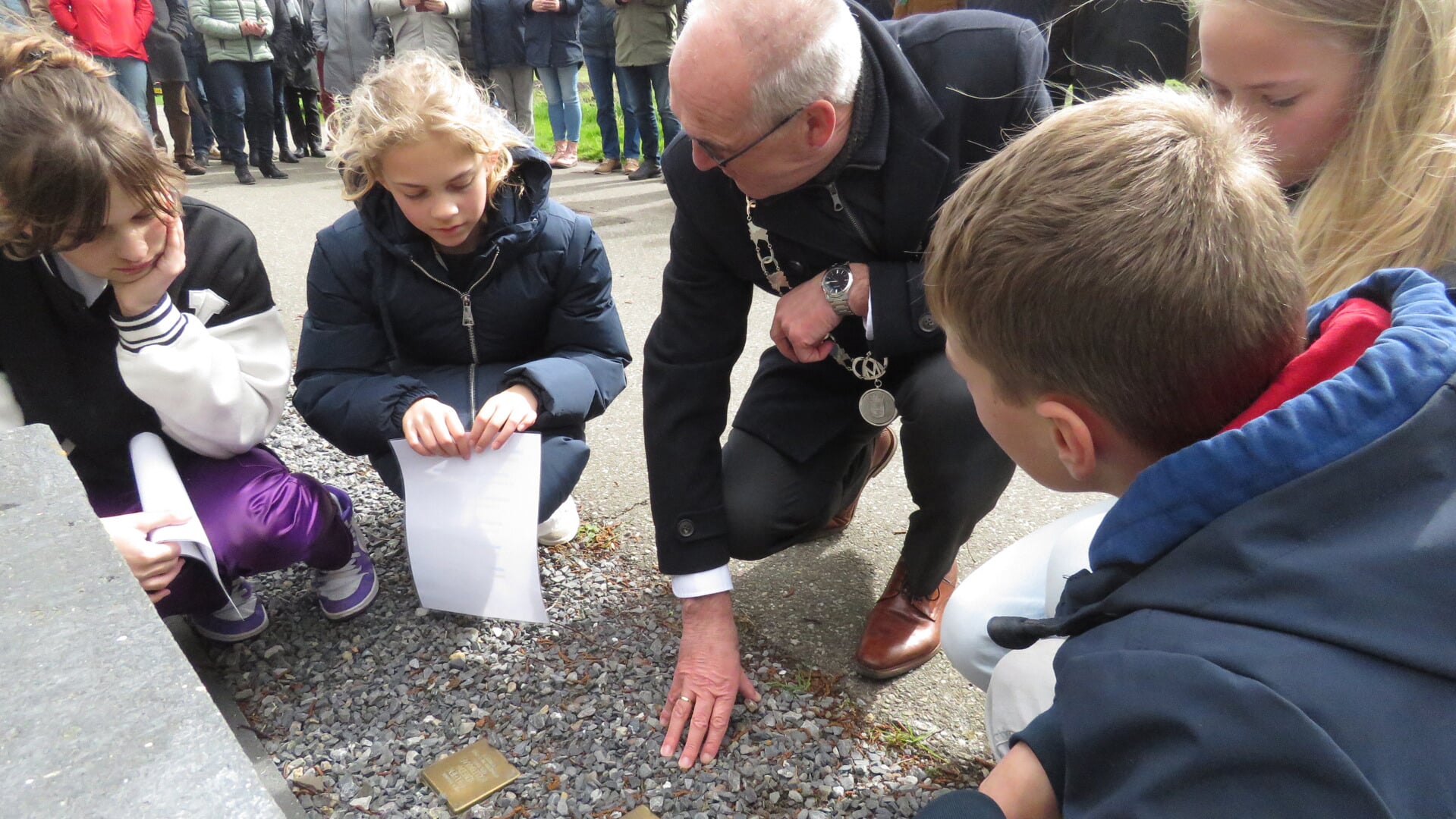 Leerlingen van de groepen 7 en 8 van basisscholen in de omgeving bekijken met de burgemeester de namen op de stenen.