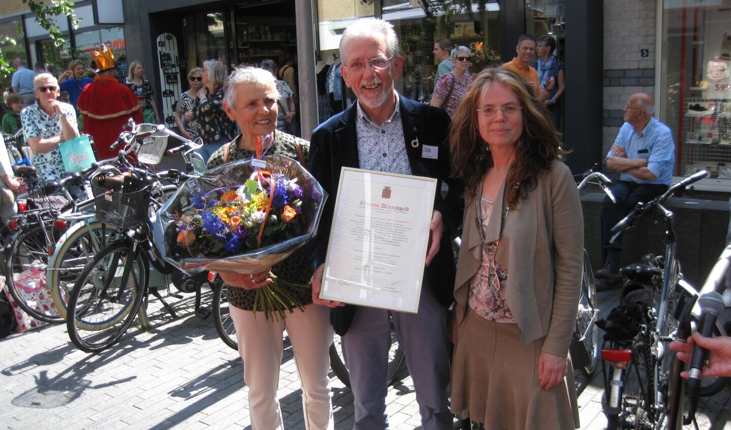 Henk Campschroer ontvangt de Zilveren Draagspeld van de burgemeester, links zijn echtgenote