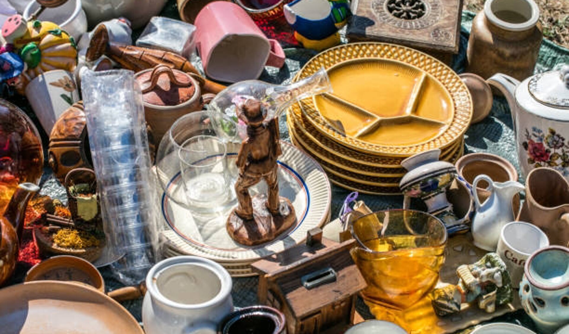 pile of household things, various dishes and decorative objects at boot sale for second hand, recycling or over-consumption society at outdoor welfare