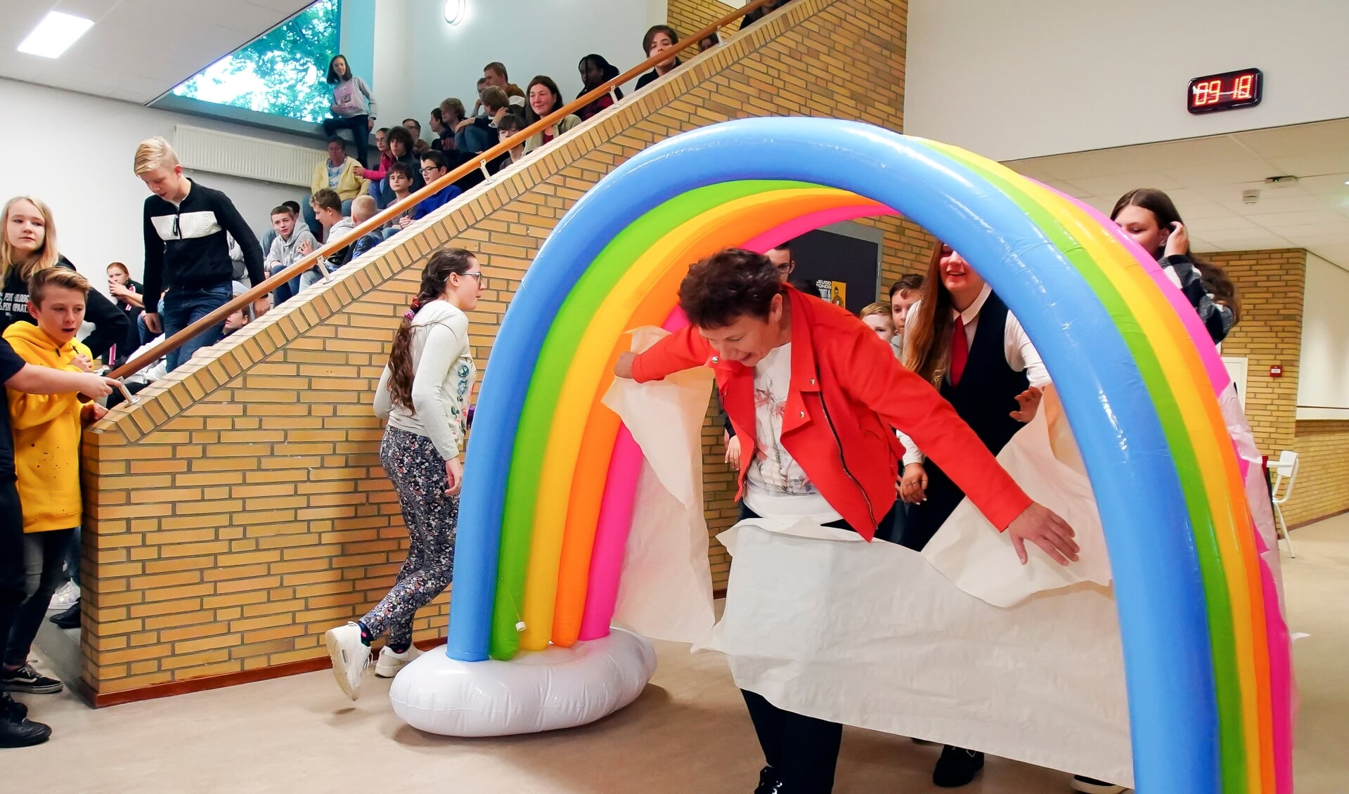 Wethouder Roelie Bosch opende het nieuwe schoolgebouw door de symbolische Regenboogpoort open te breken. (Foto: Fred Rotgans)
