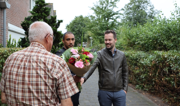 De bewoners, die niet herkenbaar op de foto wil, kreeg een bloemetje als dank. (Foto: Studio Rotgans/RInus Lettinck)